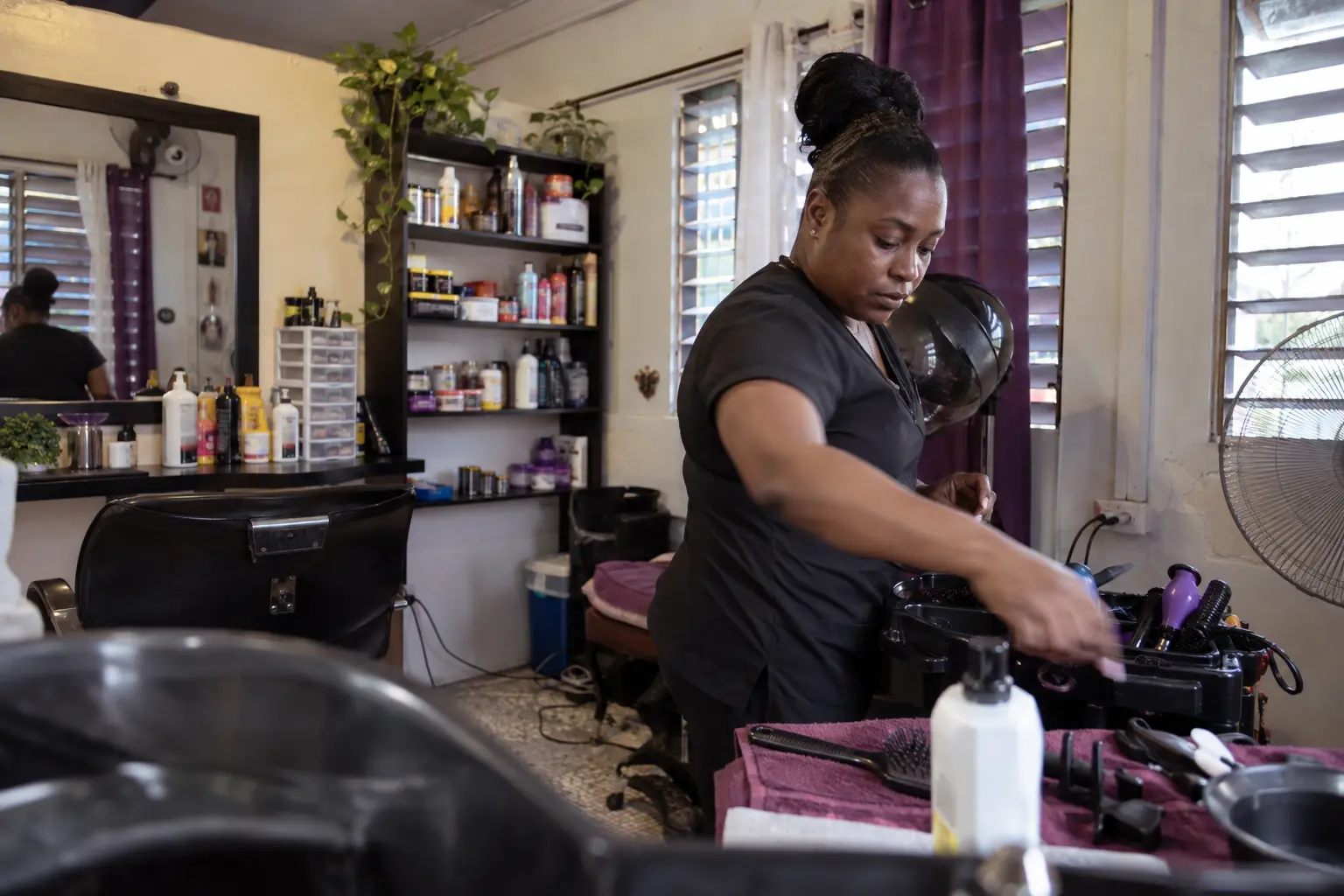 A Caribbean beauty professional preparing her salon for the workday.
